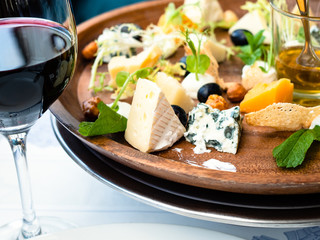 cheese plate appetizer and red wine glass close up