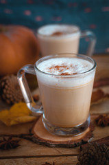 Pumpkin spice latte in glass cups, on wooden background