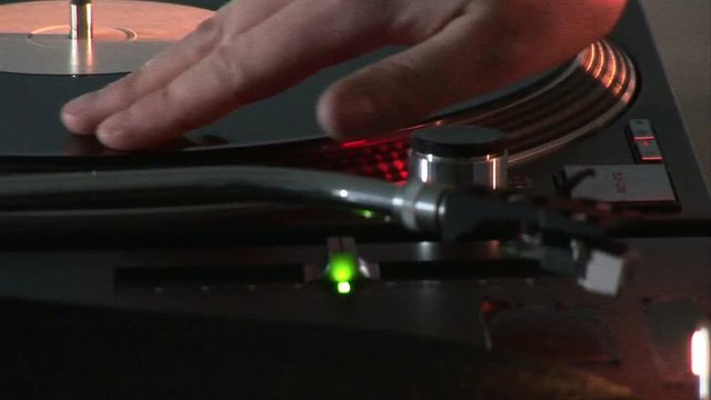 Loop of Close up of a dj scratching a disc on his mixer during a party