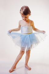 Fototapeta premium Cute child girl in light blue dress plays in the ballet.