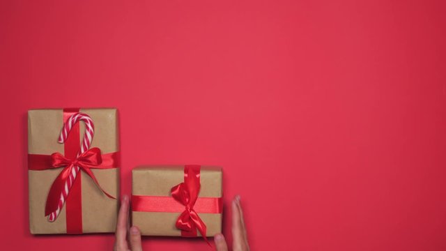 Woman hands taking away group of gift boxes over red flat lay