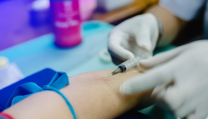 Selective and close up nurse pricking needle syringe in the arm patient drawing blood sample