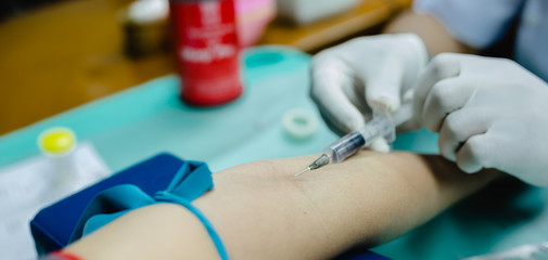 Selective and close up nurse pricking needle syringe in the arm patient drawing blood sample