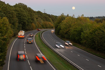 British dual carriageway road during sunset with rising full moon in the background