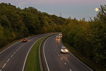 British dual carriageway road during sunset with rising full moon in the background