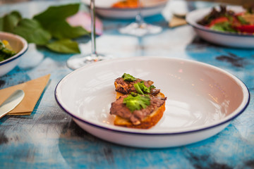 Bruschetta on a white plate in a restaurant. With meat
