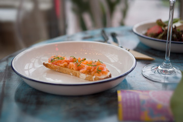 Bruschetta on a white plate in a restaurant. With fish