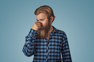 man pinches nose looks with disgust something stinks bad smell