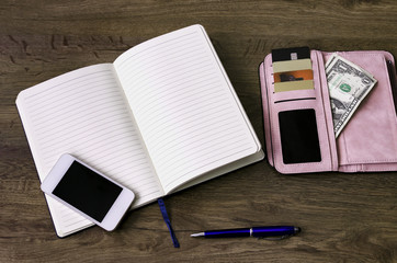 notebook with a pen, a wallet with money and discount cards,
