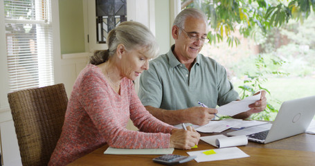 Senior couple paying bills together on laptop