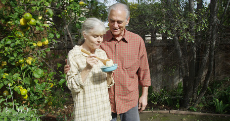 Senior couple standing eating in garden