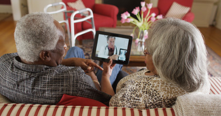 Elderly African couple video chat with a doctor on a tablet