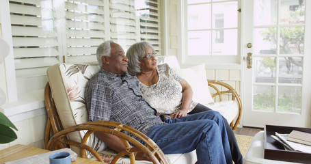 Mature black couple sitting on couch looking away - Powered by Adobe