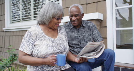 Happy retired African American couple reading newspaper