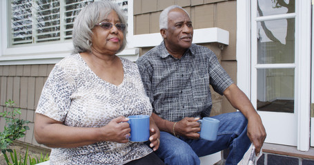 Eldlerly black couple having a drink outside home