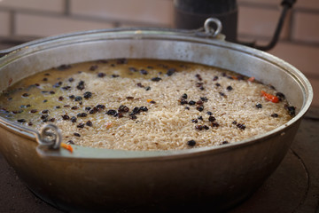 Fulvous rice, barberry and other ingredients of delicious Asian pilaf are cooked in meat broth in large cast-iron beck