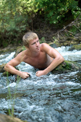 young sports man resting and bathing in the wild