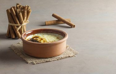 Baked rice pudding turkish milky dessert sutlac in earthenware casserole with cinnamon sticks