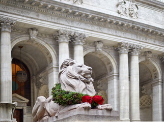 statue of the lion in the new york library decorated for christmas