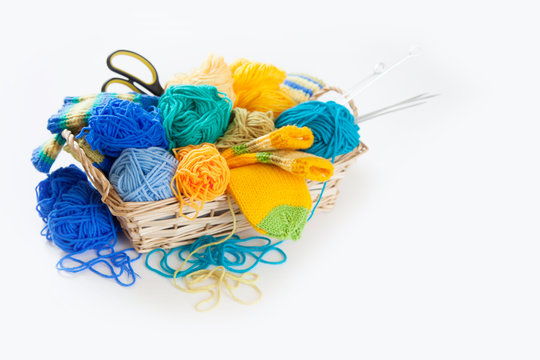 Knitting for children. Bright striped socks. Colored yarn. White background. Wicker basket.