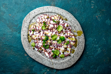 OCTOPUS CARPACCIO. Seafood Raw octopus slices with olive oil, lemon and capers on gray stone plate....