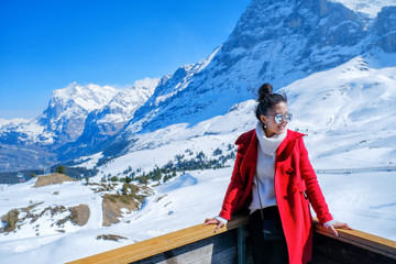 Young beautiful woman with snow mountains background at Kleine Scheidegg in winter, Switzerland