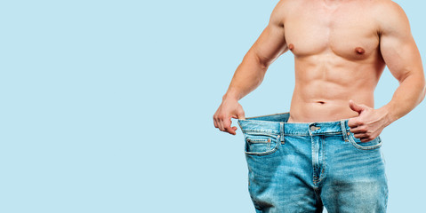 Man wearing big jeans after diet on blue background