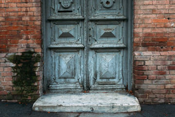 Old gray door with patterns. Brick wall.