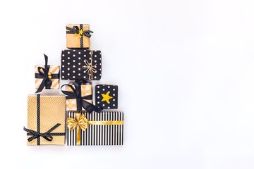 Gift boxes in various black, white and golden designs arranged in triangular shape like Christmas tree or birthday cake. A concept of Christmas, New Year, birthday celebration event. 