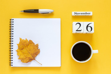 Autumn composition. Wooden calendar November 26 cup of coffee, empty open notepad with pen and yellow oak leaf on yellow background. Top view Flat lay Mockup Concept Hello November