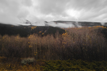 Mountains covered in low hanging clouds during autumn in Colorado. 