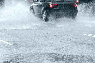car driving In high speed through big water puddle during heavy rain making water splashes
