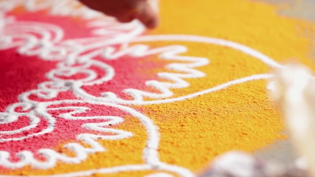 Rangoli with coloured powder being created by Rangoli artist on occasion of Hindu festival, Mumbai, Maharashtra, India.
