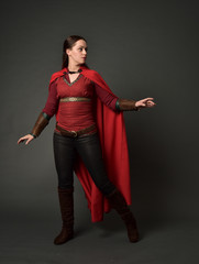 full length portrait of brunette girl wearing red medieval costume and cloak. standing pose   on...