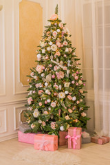 Pastel christmas.Elegant christmas tree with decorations and gifts on elegant hardwood floor. Pink Christmas gift boxes with pink and silver ribbon next to decorated Christmas tree. Candy pink,soft
