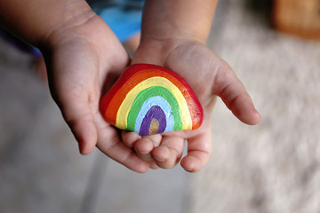 Young Child's LIttle Hands Holding Painted Rainbow Rock