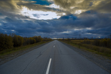 Asphalt road with intermittent dividing strip along the autumn forest