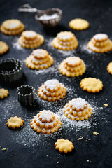 Fresh baked traditional christmas vanilla jam cookies sprinkled with powdered sugar on rustic black background. Selective focus.