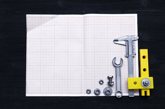 Graph paper for project drafts and a different construction tools on the builder table. Construction background with copy space.