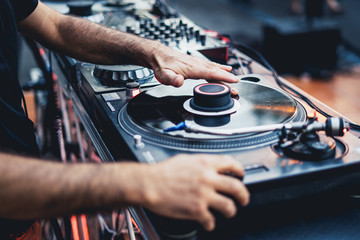dj scratching a vinyl disc on a professional turntable, focus on the left hand scratching.