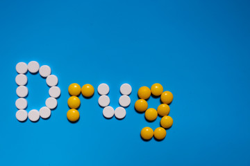 word Drugs from Color capsules on the blue background. top view copy space pattern