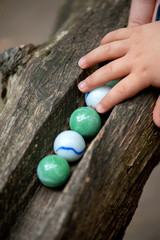 Kinderhand und Glaskugeln auf der Holzkugelbahn