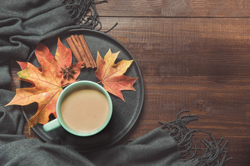 Autumn still life with cup of coffee, colorful dry leaves warm scarf on wooden board. Copy space. Top view.