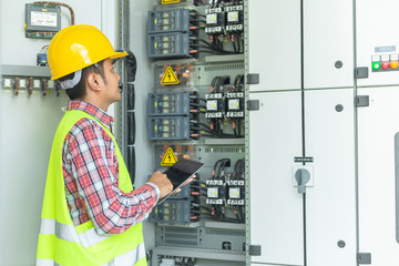 Asian maintenance engineers inspect relay protection system with laptop computer. Bay control unit. Medium voltage switchgear.
