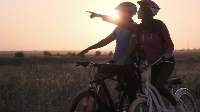 A married couple are discussing the route on bikes against the rising sun.