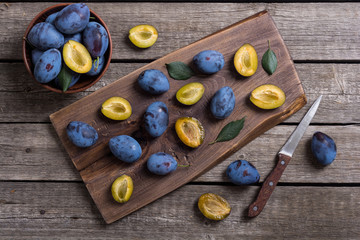 Fresh plums in bowl on wooden table