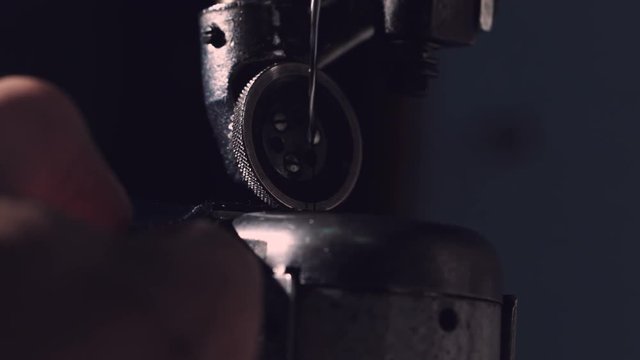 The master makes shoes in the workshop. Side view of using sewing machine to make seam. Closeup slowmotion. 4K