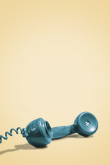 Vintage green rotary phone handset on a retro yellow background with space for copy and text