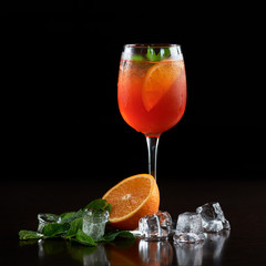 Composition with crystal cocktail glass with cold drink, slice of orange, fresh green mint leaves...