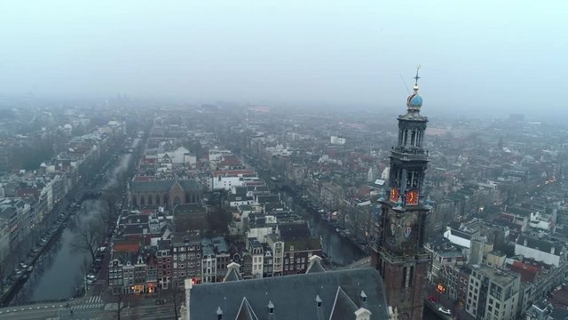Above view Westerkerk Church tower in Amsterdam. Flying arround clock tower at background cityscape in light haze